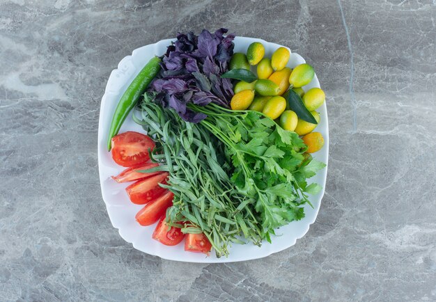 Plato lleno de verduras mixtas, sobre la mesa de mármol.