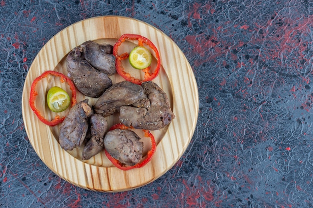 Foto gratuita un plato de madera de chuleta de pollo con tomate en rodajas.