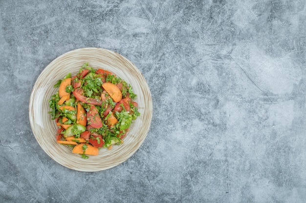 Un plato de madera de deliciosa ensalada de verduras.