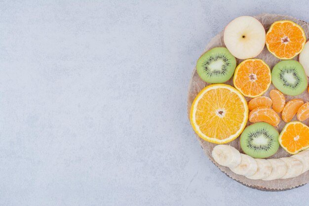 Un plato de madera de frutas en rodajas sobre fondo blanco. Foto de alta calidad