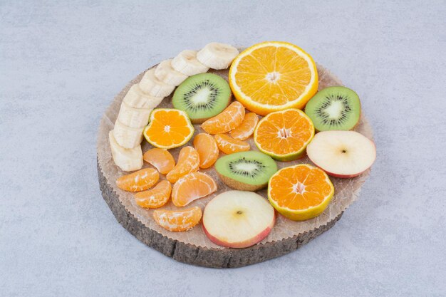 Un plato de madera de frutas en rodajas sobre fondo blanco. Foto de alta calidad
