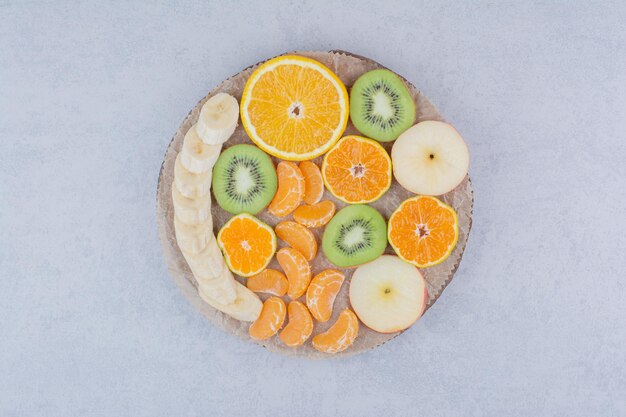 Un plato de madera de frutas en rodajas sobre fondo blanco. Foto de alta calidad