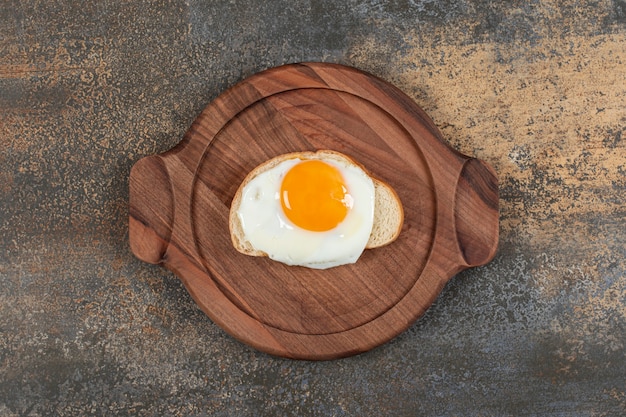 Un plato de madera de huevo en la rebanada de pan blanco.
