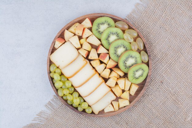 Un plato de madera lleno de frutas en rodajas y pan. Foto de alta calidad