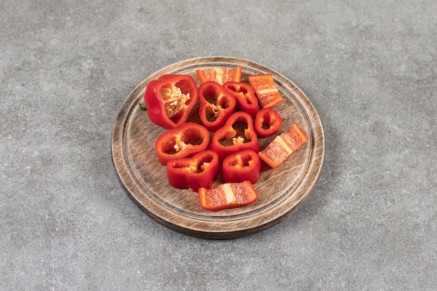 Foto gratuita un plato de madera lleno de pimiento rojo picado colocado sobre una superficie de piedra.