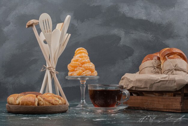 Plato de madera de panadería con utensilios de cocina en mármol.