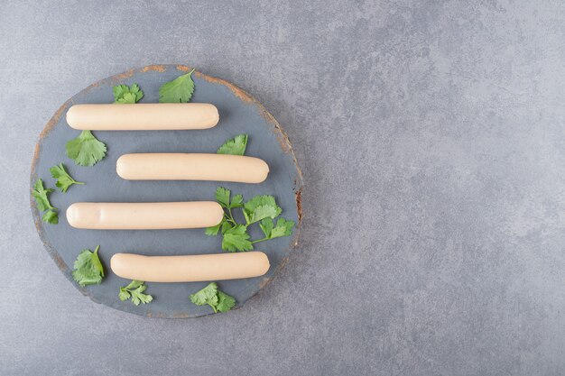 Un plato de madera con salchichas hervidas y perejil.