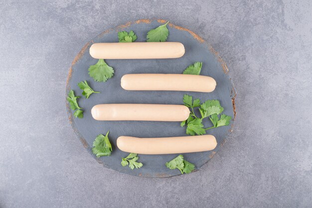 Un plato de madera con salchichas hervidas y perejil.