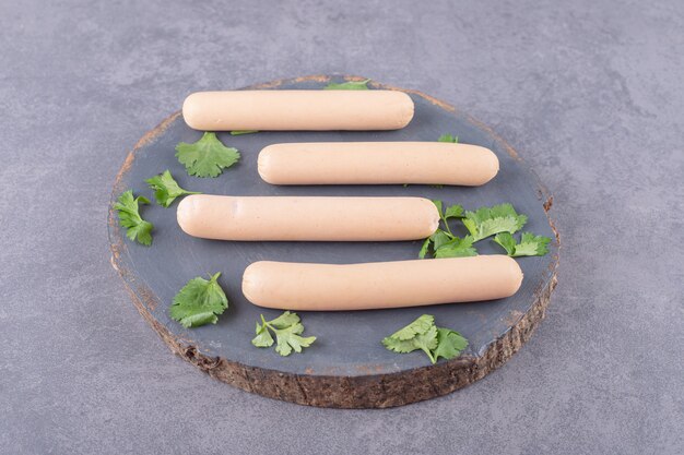 Un plato de madera con salchichas hervidas y perejil.