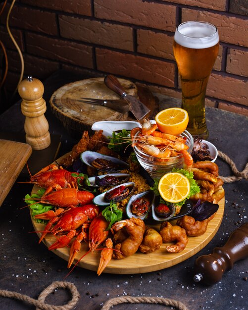 Plato de mariscos con camarones, mejillones, langostas servidos con limón y cerveza