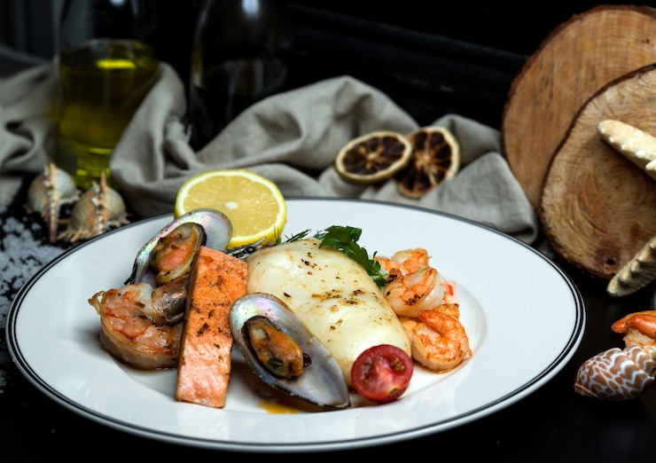 Foto gratuito plato de mariscos con salmón frito, mejillones, camarones, calamares y limón.