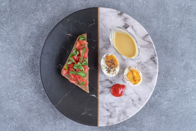 Un plato de mármol con huevo cocido y tostadas. Foto de alta calidad