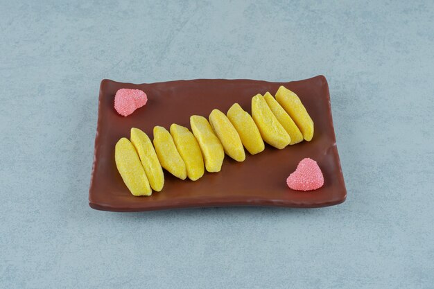 Un plato marrón de caramelos masticables en forma de plátano con caramelos de gelatina azucarados en forma de corazón