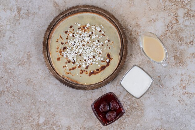 Un plato marrón de sabrosas crepas y mermelada de fresa.