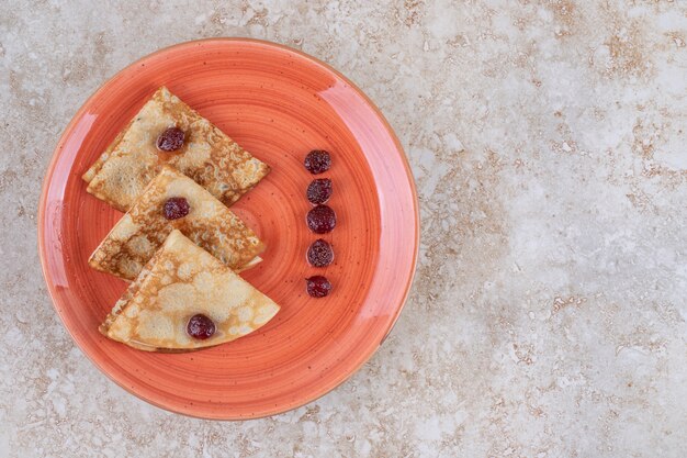 Un plato de naranja con deliciosos panqueques finos y bayas