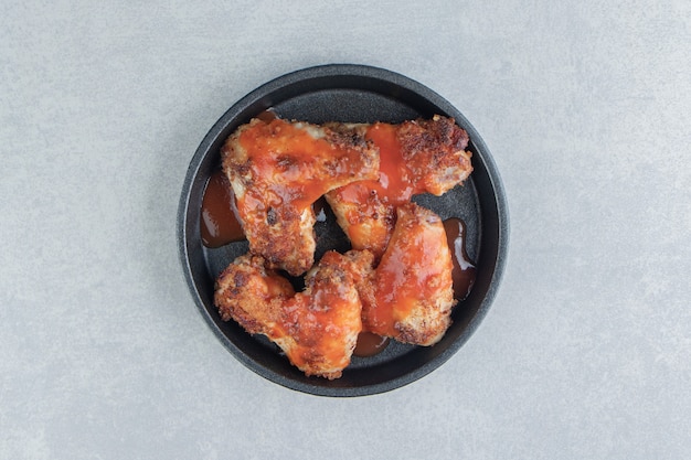 Un plato negro de carne frita en salsa de tomate.