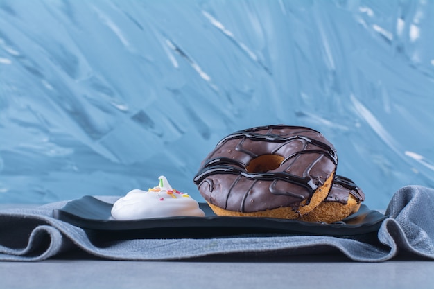 Foto gratuita un plato negro de donas de chocolate dulce sobre un mantel.