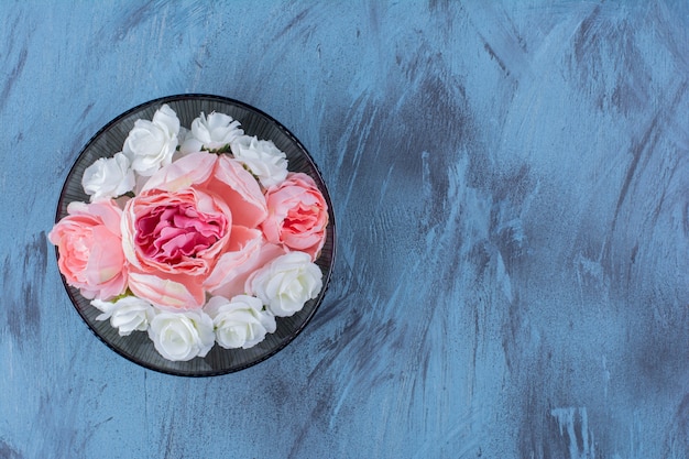 Un plato negro con flor violeta sobre azul.