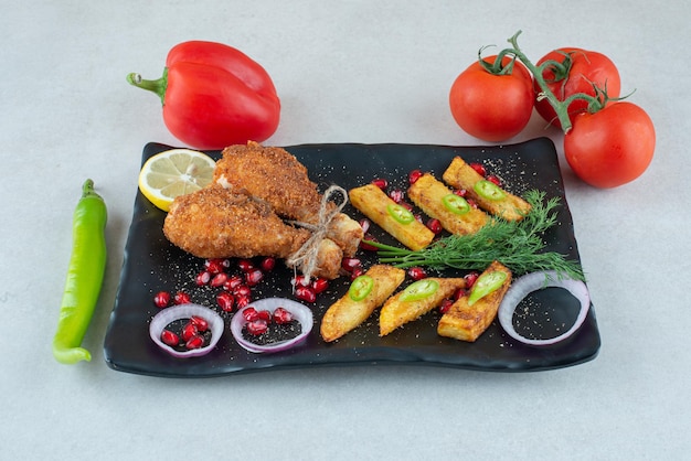 Un plato negro lleno de pollo frito con tomate y pimiento.