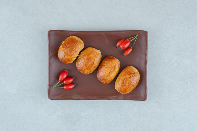 Un plato oscuro de deliciosas galletas dulces con rosa mosqueta.