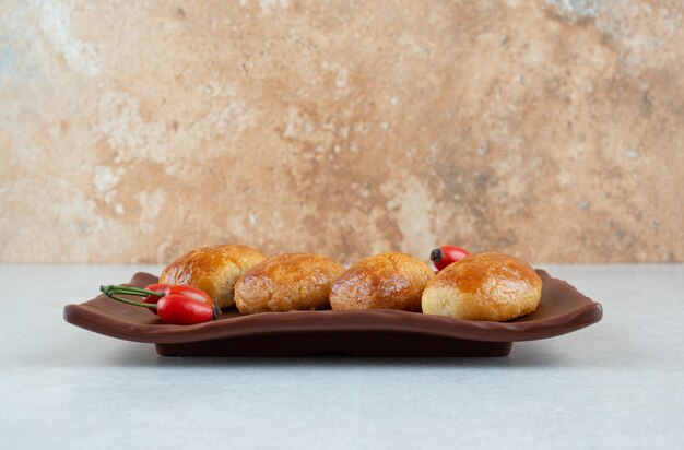 Un plato oscuro de deliciosas galletas dulces con rosa mosqueta.