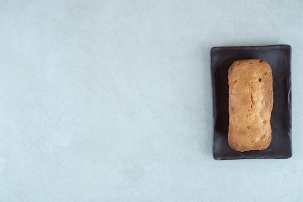 Un plato oscuro con un delicioso pastel fresco en blanco