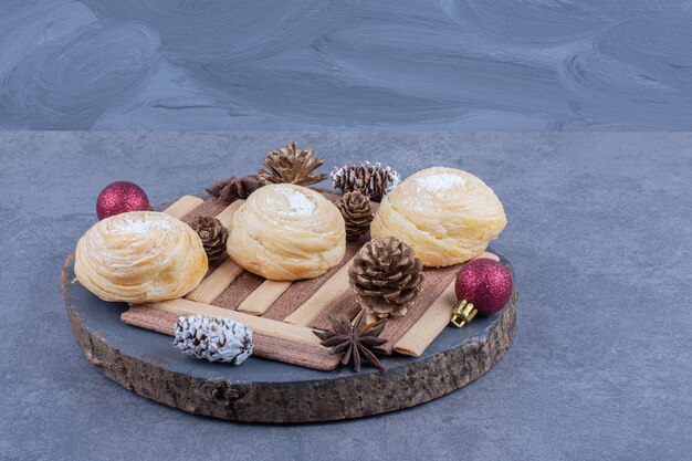 Un plato oscuro con galletas y piñas navideñas.