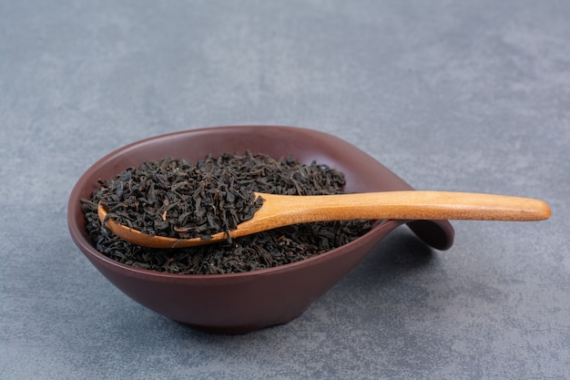 Un plato oscuro lleno de infusión con cuchara de madera.