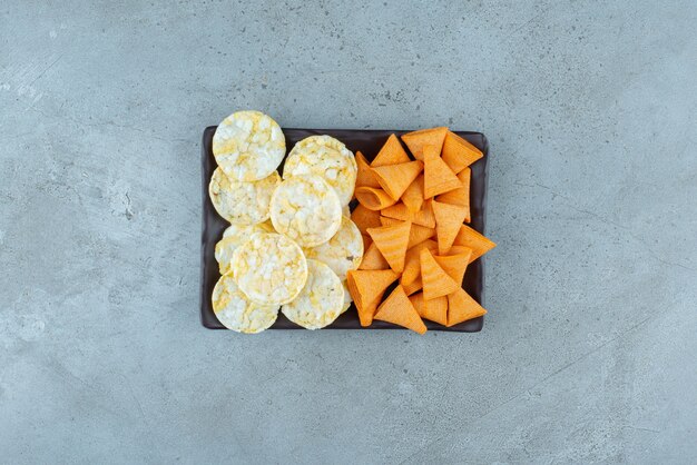 Un plato oscuro lleno de patatas fritas crujientes sobre fondo gris. Foto de alta calidad