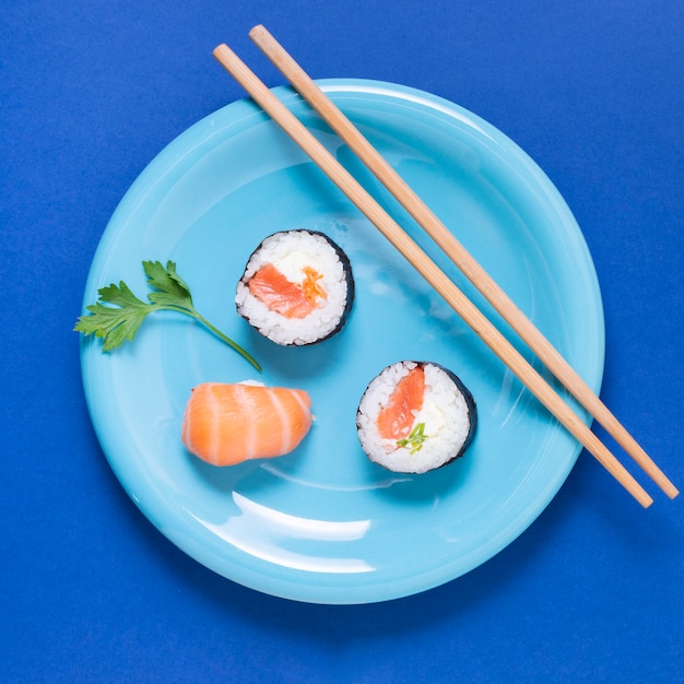 Foto gratuita plato con palillos y rollos de sushi