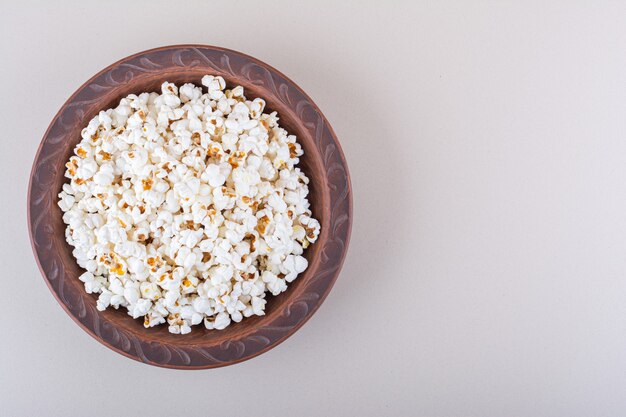 Plato de palomitas de maíz saladas para noche de cine sobre fondo blanco. Foto de alta calidad