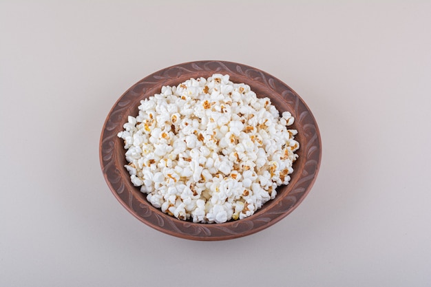 Plato de palomitas de maíz saladas para noche de cine sobre superficie blanca. Foto de alta calidad