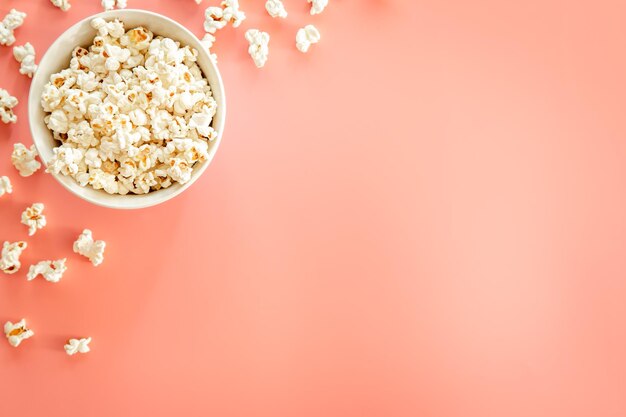 Plato de palomitas de maíz sobre fondo rosa plano