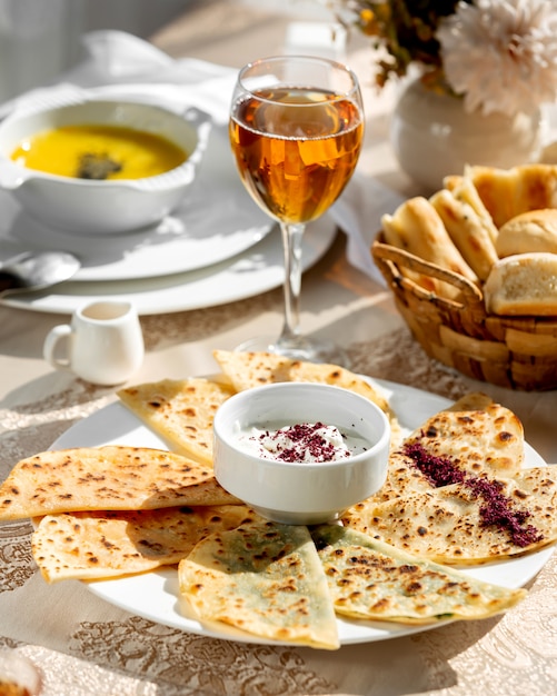 Un plato de pan plano relleno de gutab azerbaiyano servido con yogur