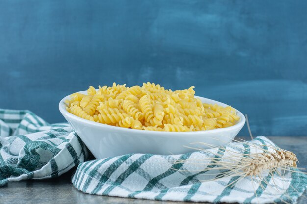 Un plato de pasta junto a dos trigo sobre la toalla, sobre el fondo de mármol.