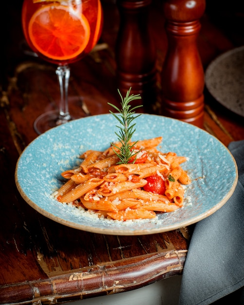 Un plato de pasta penne con salsa de tomate y parmesano.