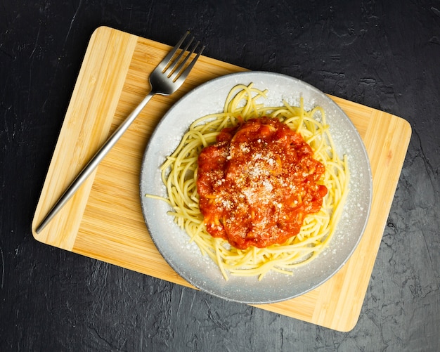 Plato de pasta sobre tabla de cortar con tenedor