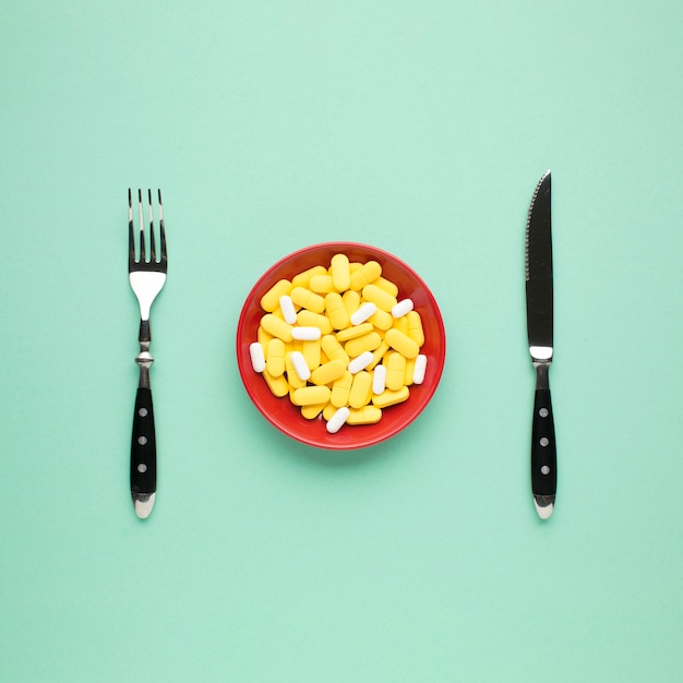 Foto gratuita plato de pastillas amarillas y blancas con cubiertos sobre fondo verde