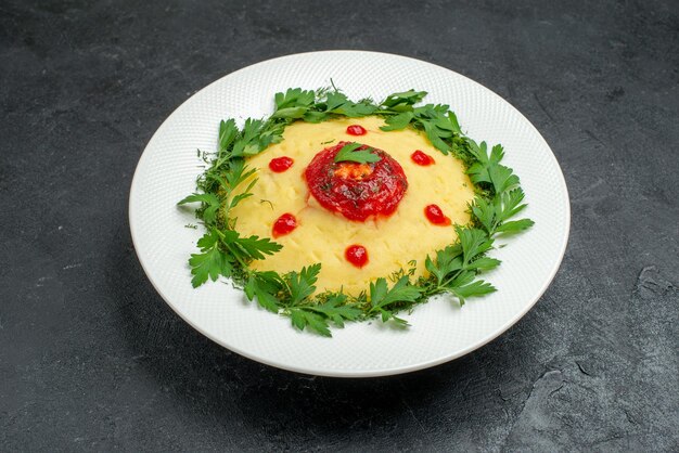 Plato de patata triturada vista frontal con salsa de tomate y verduras en el espacio oscuro