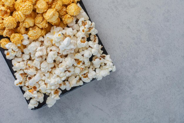 Plato pequeño de palomitas de maíz dulces y palomitas de maíz saladas en la superficie de mármol