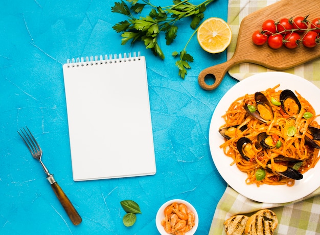 Plato plano de pasta de mejillones con cuaderno.