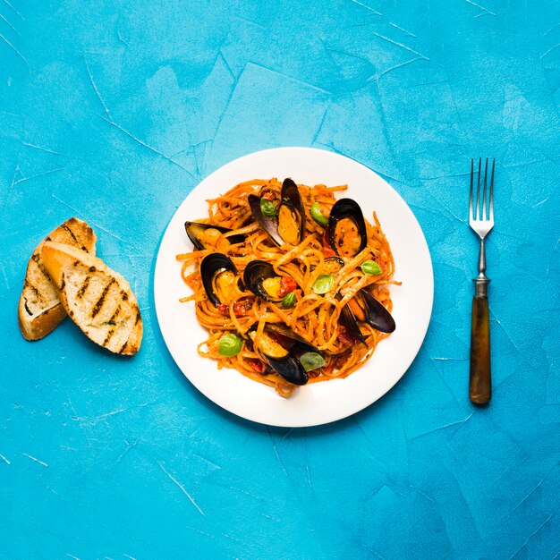 Foto gratuita plato plano de pasta con mejillones y tenedor.