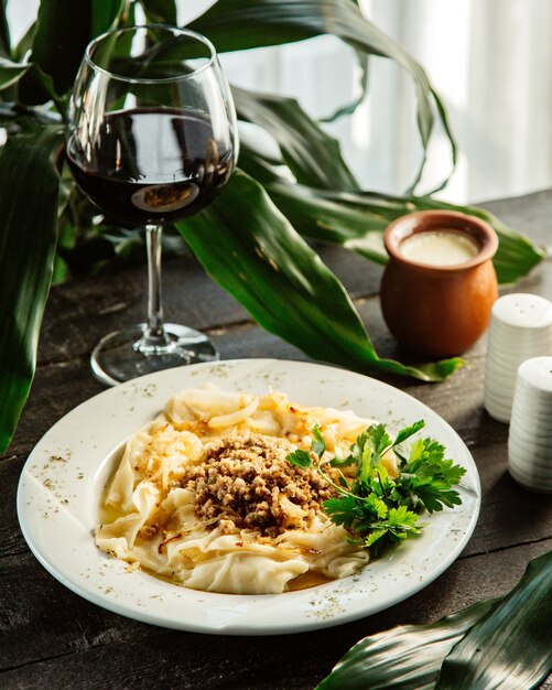 Un plato de plato azerbaiyano pasta cuadrada khangal servido con carne picada y cebolla