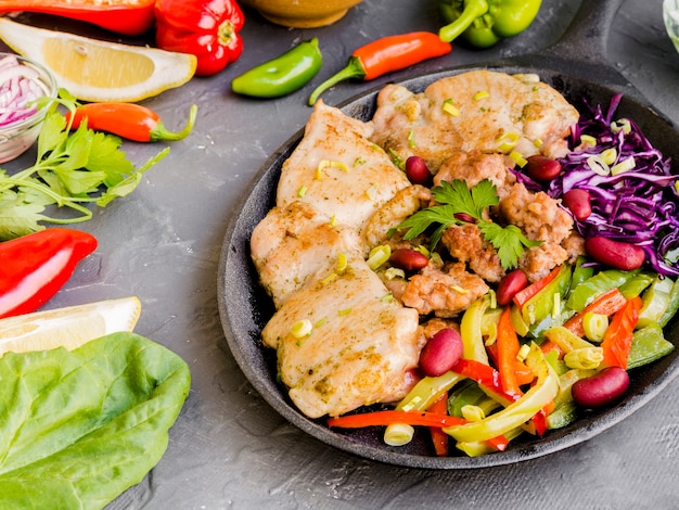 Plato con plato de carne junto a verduras y limones.