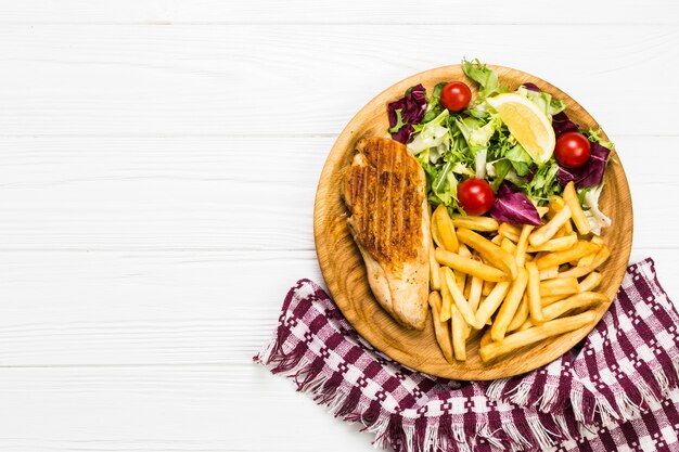 Plato con pollo y ensalada cerca de la servilleta