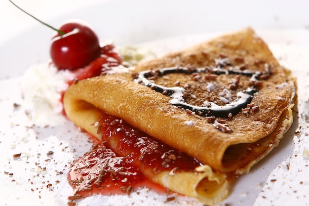 Plato de postre con panqueques y cerezas