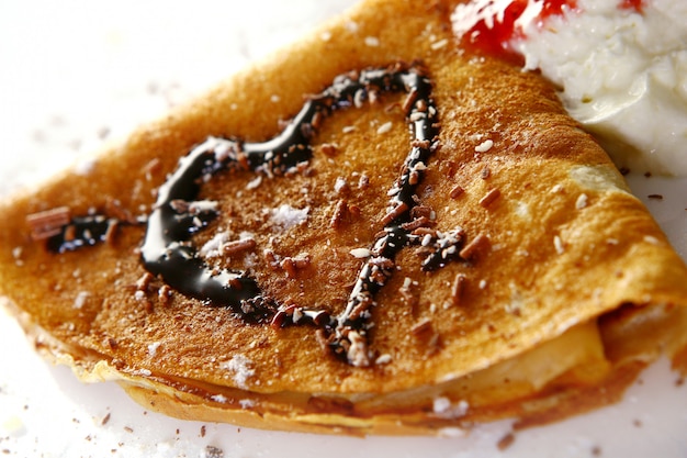 Plato de postre con panqueques y jarabe de chocolate