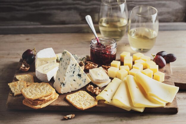 Plato de queso con diferentes artes de uva de queso y nueces servido en tablero de madera