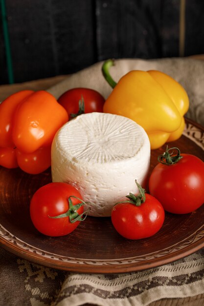 Plato de queso con tomate y pimientos sobre una toalla rústica