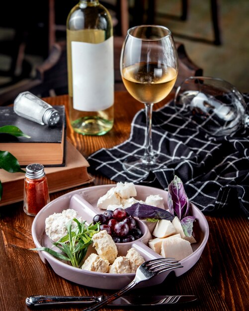 Plato de queso con uvas y vino blanco.